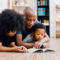 African American father reading a fairy tale fable story to kid with mom African American father reading a fairy tale fable story to kid with mom