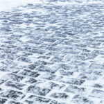 Cobblestone sidewalk covered with ice and snow