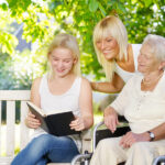 Daughter is reading to elder guardian and elder outside Daughter is reading to elder guardian and elder outside