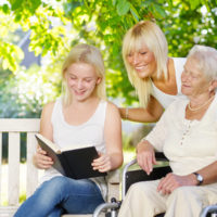 Daughter is reading to elder guardian and elder outside Daughter is reading to elder guardian and elder outside