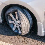 Car tire that has a blowout with rim and car damage Car tire that has a blowout with rim and car damage