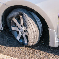 Car tire that has a blowout with rim and car damage