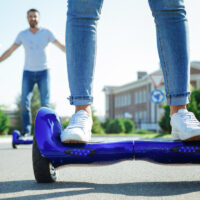 Man and woman riding hoverboard down the street