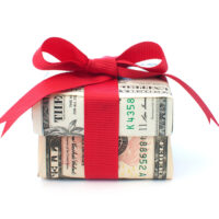 Dollar wrapped gift box with a red ribbon bow Dollar wrapped gift box with a red ribbon bow