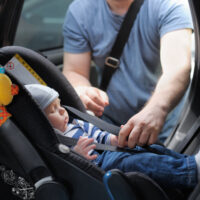 Father straping baby in car seat Father straping baby in car seat