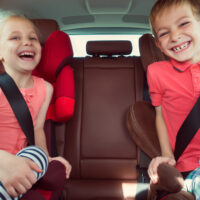 Two kids wearing seat belts
