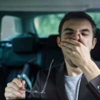 drowsy driver yawning with hand to mouth