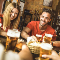 Happy friends group drinking beer at brewery bar restaurant - Friendship concept with young people enjoying time together and having genuine fun at cool vintage pub - Focus on guy - High iso image