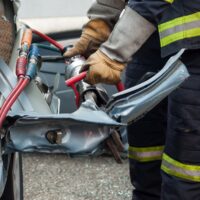 closeup of french rescue man with pneumatic machine on crashed car