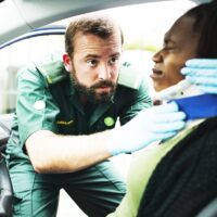 Paramedic placing a cervical collar to an injured woman from car Paramedic placing a cervical collar to an injured woman from car