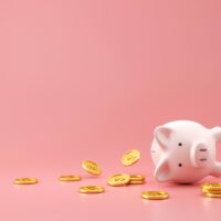 Piggy bank and golden coins on pink background with lost money c