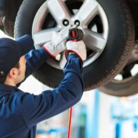 Mechanician changing car wheel in auto repair shop Mechanician changing car wheel in auto repair shop