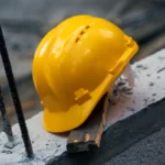 Construction hard hat safety tools equipment for workers in construction site for engineering protection head standard on building construction background. Yellow helmet